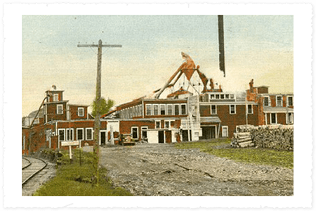 Vintage postcard of a building under construction with a statue on top, surrounded by trees and a clear sky.